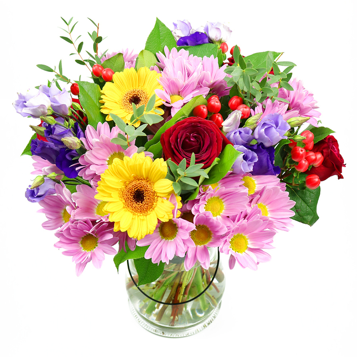A colourful, carefully composed bouquet rises from a clear glass vase, photographed against a crisp white background that highlights its form. At its heart, deep red roses unfurl like velvet, their layered petals adding richness and a sense of timeless affection. Nearby, golden yellow gerbera daisies with dark, earthy centres provide a joyful counterpoint, their large faces turned outward as if smiling. Around this central cluster, a generous scattering of soft pink daisies or chrysanthemums unfolds, each bloom made up of many fine petals radiating from tiny yellow eyes, creating a plush, cloud-like ring that gives the bouquet its full, rounded silhouette. Meandering through the pink and yellow flowers, lisianthus blooms in shades of purple and pale lavender curve gently upward, their bell-shaped, slightly ruffled petals adding elegance and depth. Interspersed among the blossoms, glossy red hypericum berries cluster tightly on their stems, offering pops of colour and an appealing, bead-like texture. The flowers are enveloped by a variety of greenery, including broad, darker leaves that anchor the design and slender, lighter green sprigs that add lightness and movement, echoing the greenery seen along the riverbanks near Egham and Runnymede. The transparent vase reveals the stems gathered and trimmed, fanning into clear water, evidence of a florist's practiced hand. The bouquet has an uplifting, celebratory mood, making it easy to picture it brightening a living room in an Egham town house or greeting someone at their office on Egham High Street. It feels ideal for birthdays, anniversaries, exam congratulations, or any occasion where you want to send a radiant expression of care.